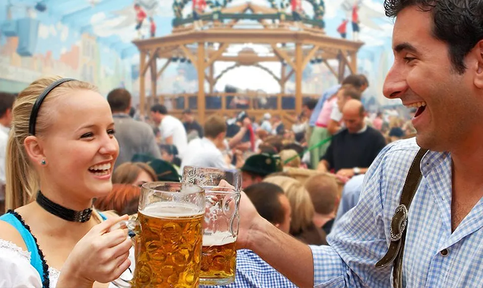 A man and a woman cheers with large mugs of beer at Oktoberfest in Germany