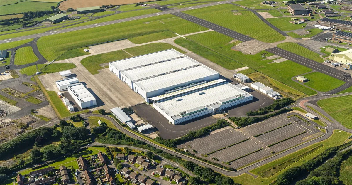 An aerial view of a factory plant for Aston Martin cars surrounded by green space and access roads.