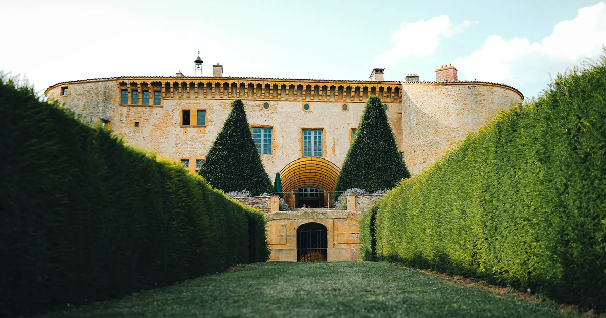 A huge stone fortress-style château with yellow detailing at Château de Bagnols.