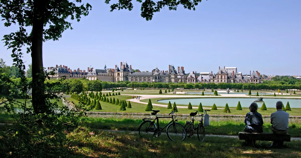 An enormous château complex with multiple buildings, lakes, pathways and manicured tree orchards.