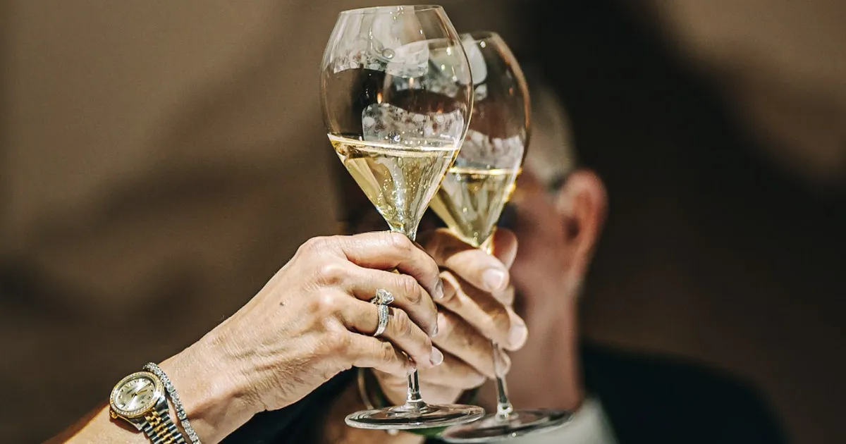 A close up of two people toasting Champagne glasses.