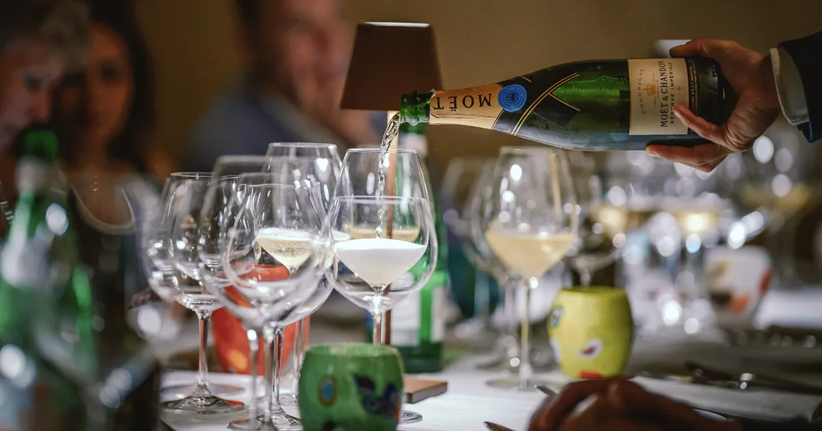 A bottle of Moët & Chandon being poured into glasses on a dinner table.