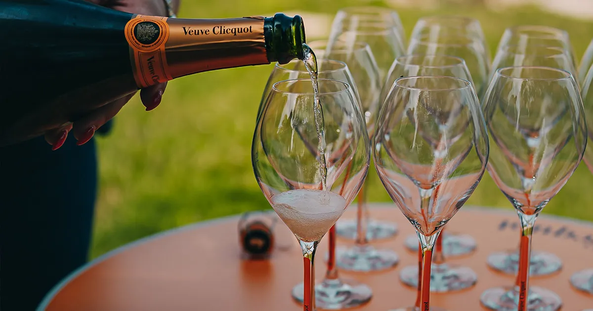 A bottle of Veuve Clicquot being poured into glasses.