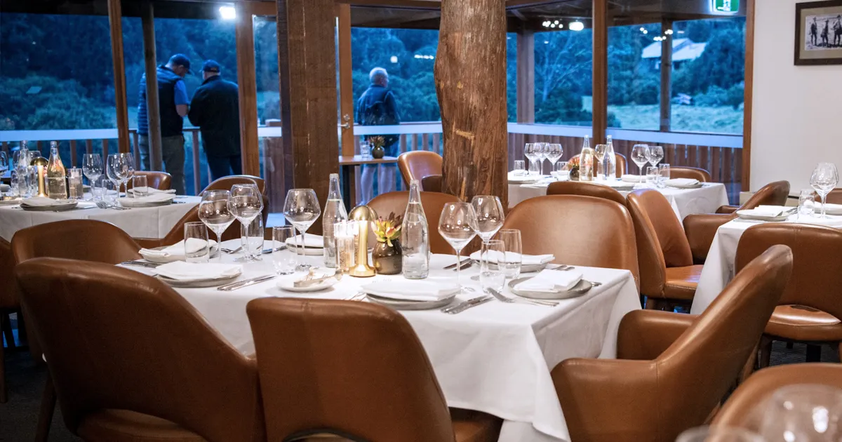 Leather-bound chairs are set around white tablecloths at Peppers Cradle Mountain. 