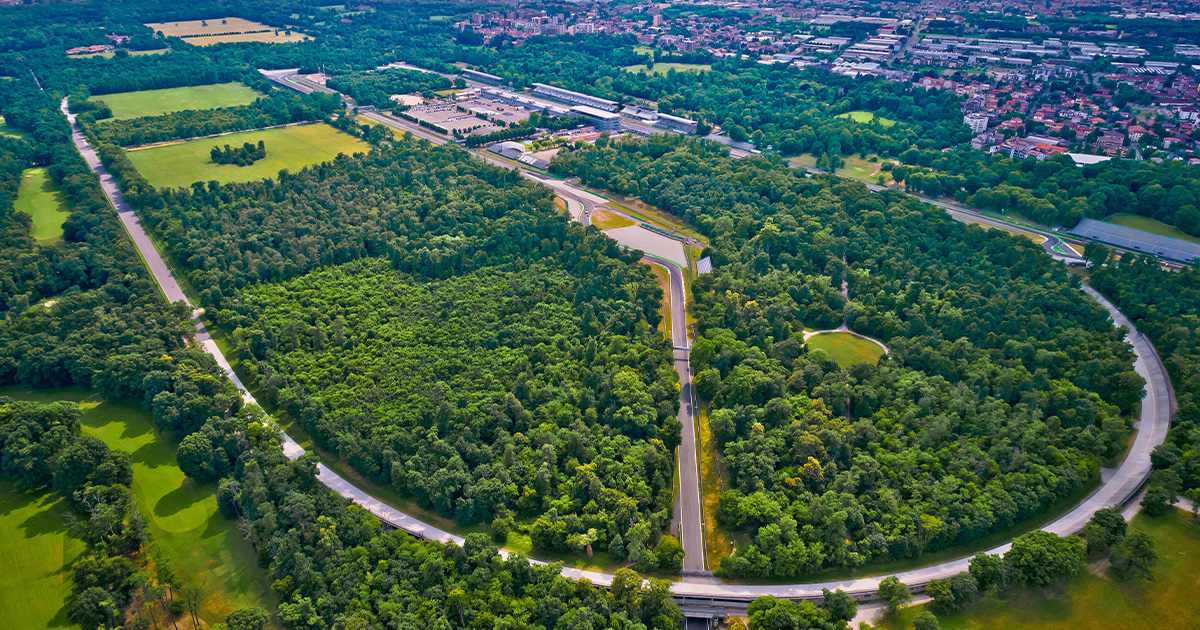 An aerial view of Monza racetrack in Italy with green lawns and trees inside the oval tarmac.