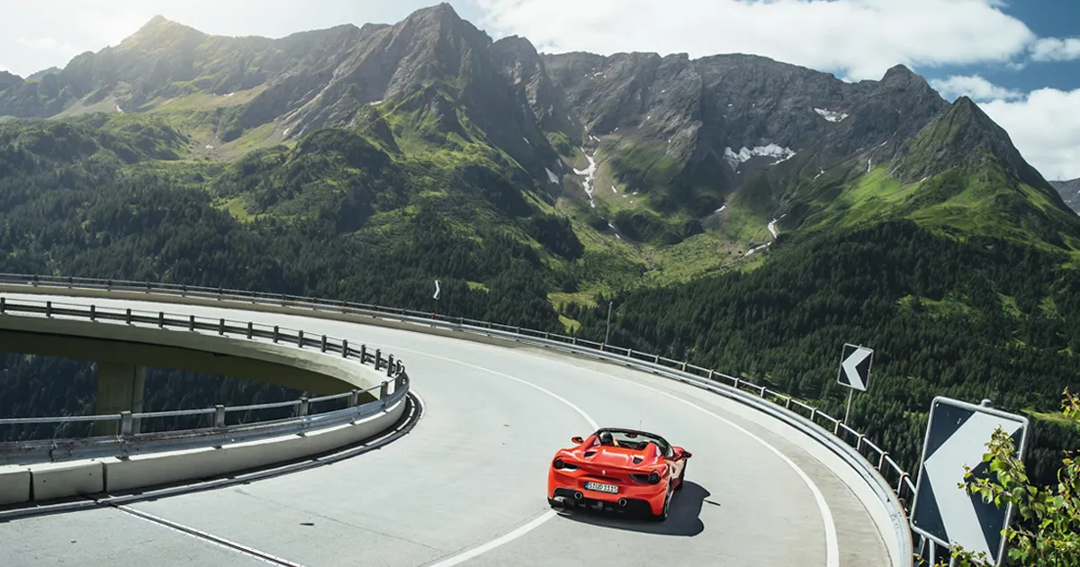 A red Ferrari navigates a sweeping corner in the mountains of Switzerland.