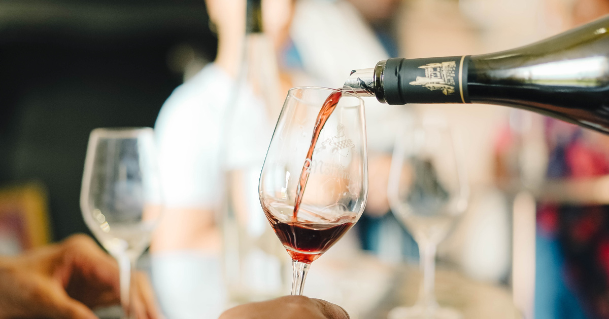 An aged French red wine is poured with a drip stopper into glass