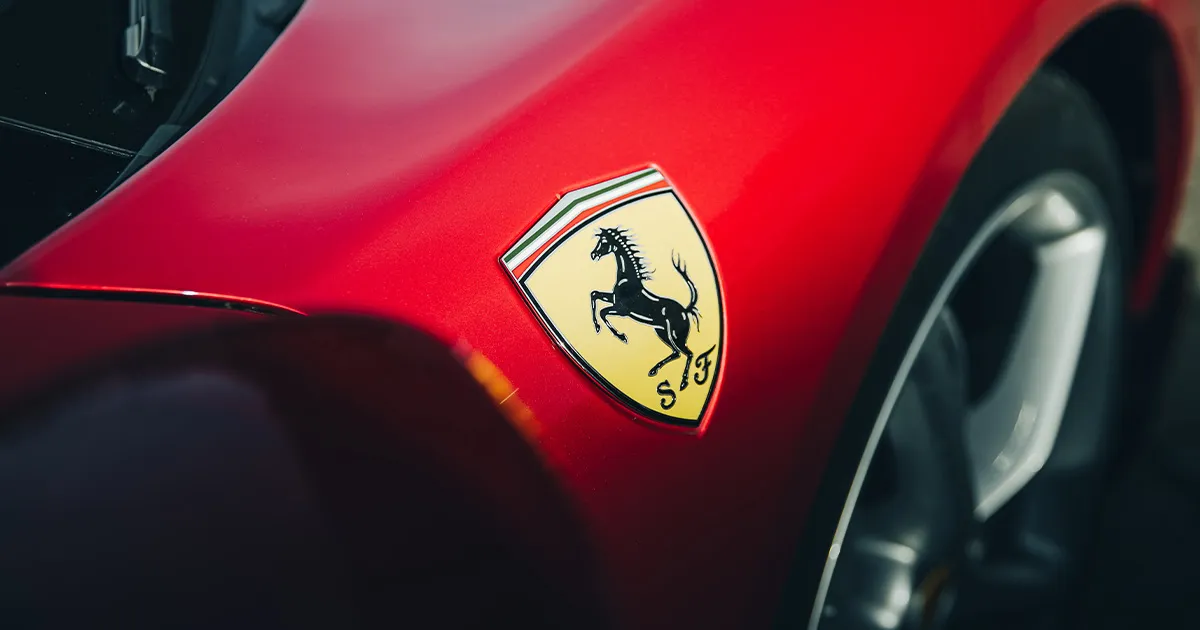 A yellow prancing horse badge on a red Ferrari’s wheel arch.