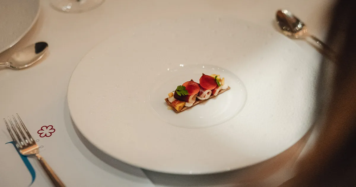 An artistically plated small starter dish on a large white plate at a fine dining restaurant