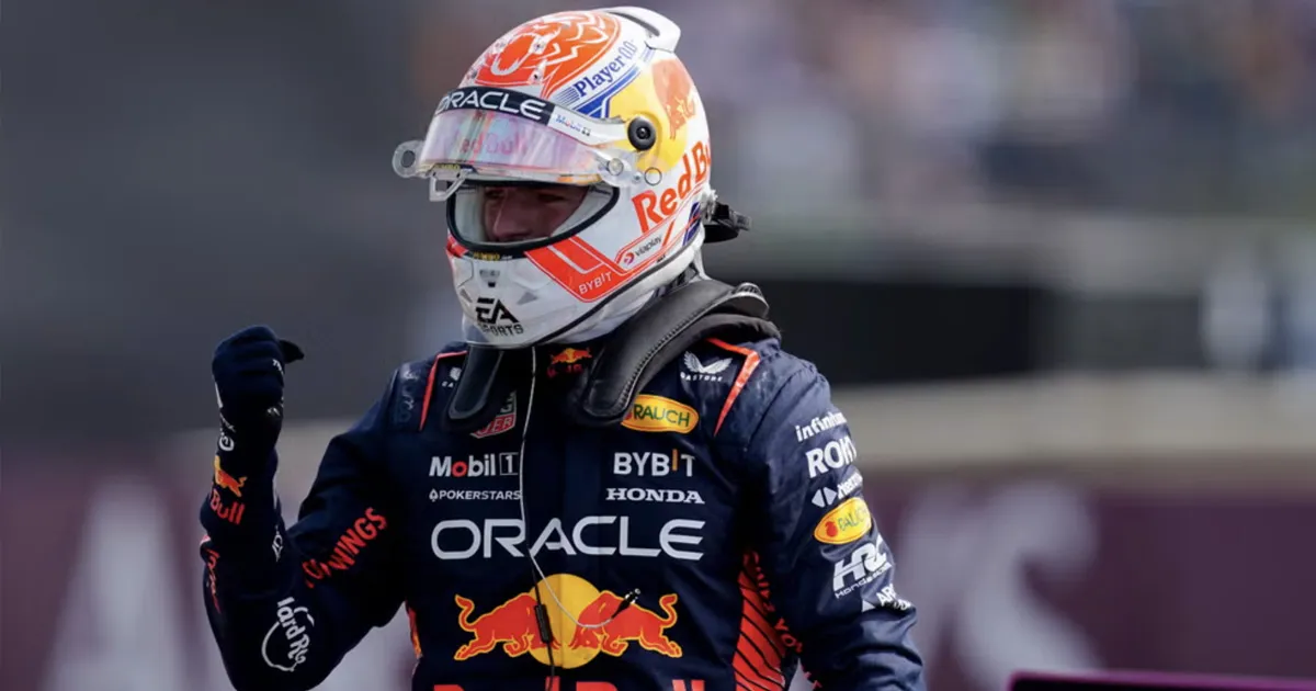 Max Verstappen standing in full race gear with his fist clenched