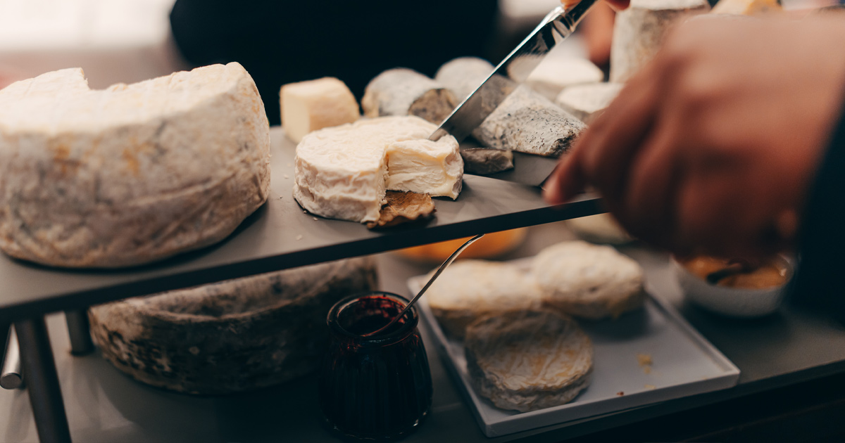 Goats cheese being cut into portions on a black serving board