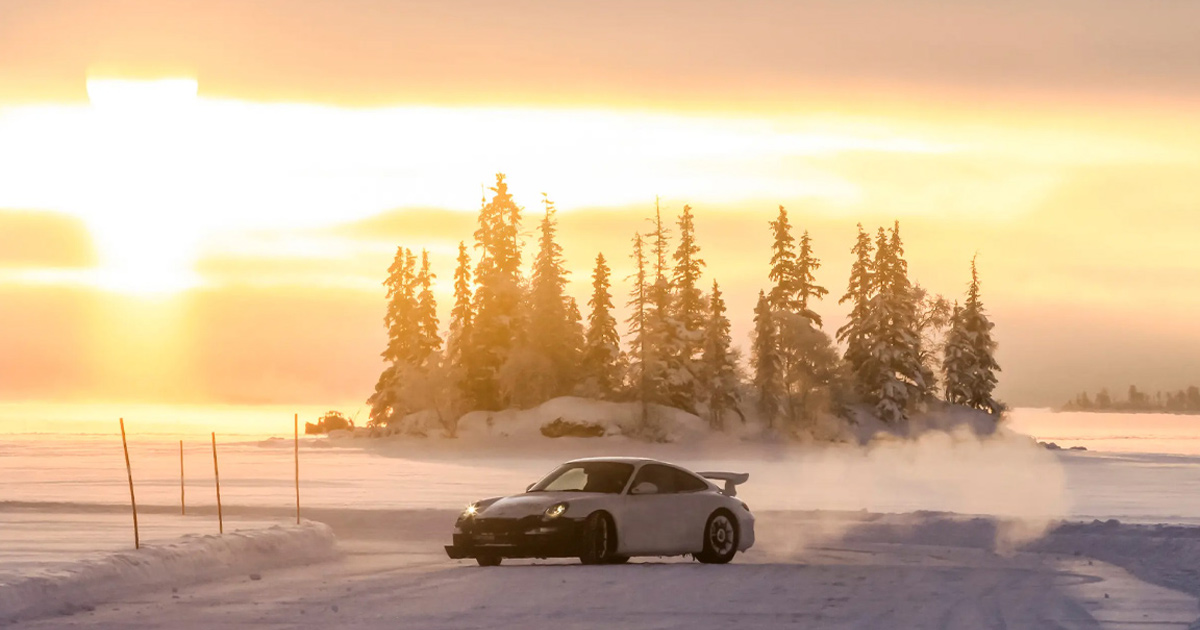 A specially prepared Porsche 911 drifting on ice with a gorgeous sunset behind
