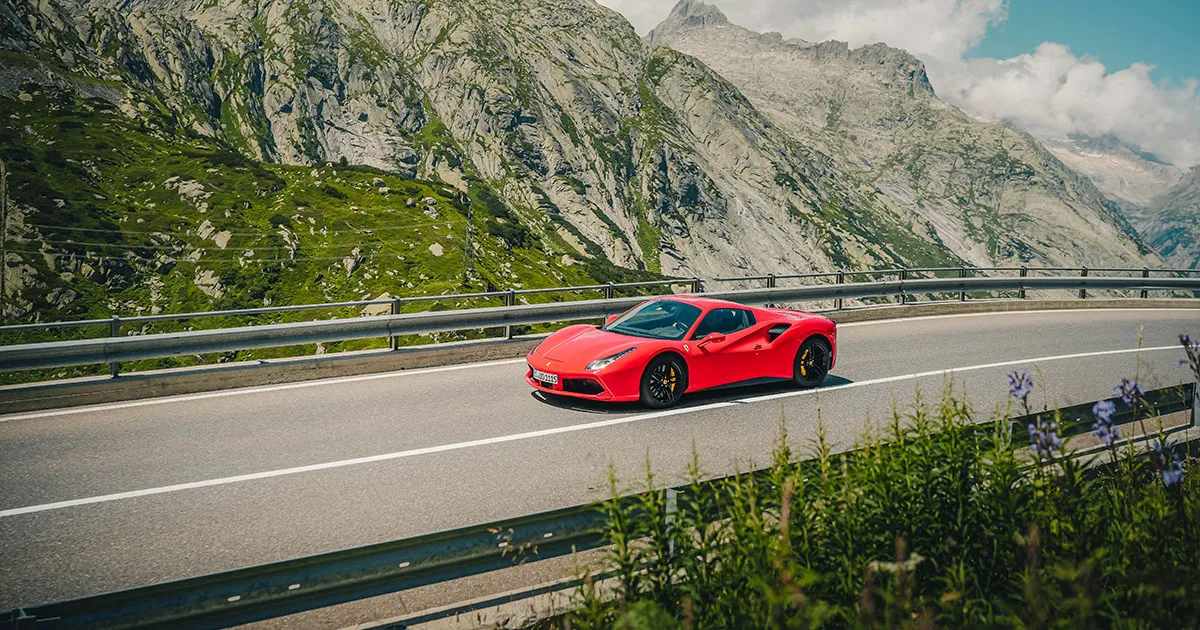 A red Ferrari 488 rounding a corner on a Swiss alpine road