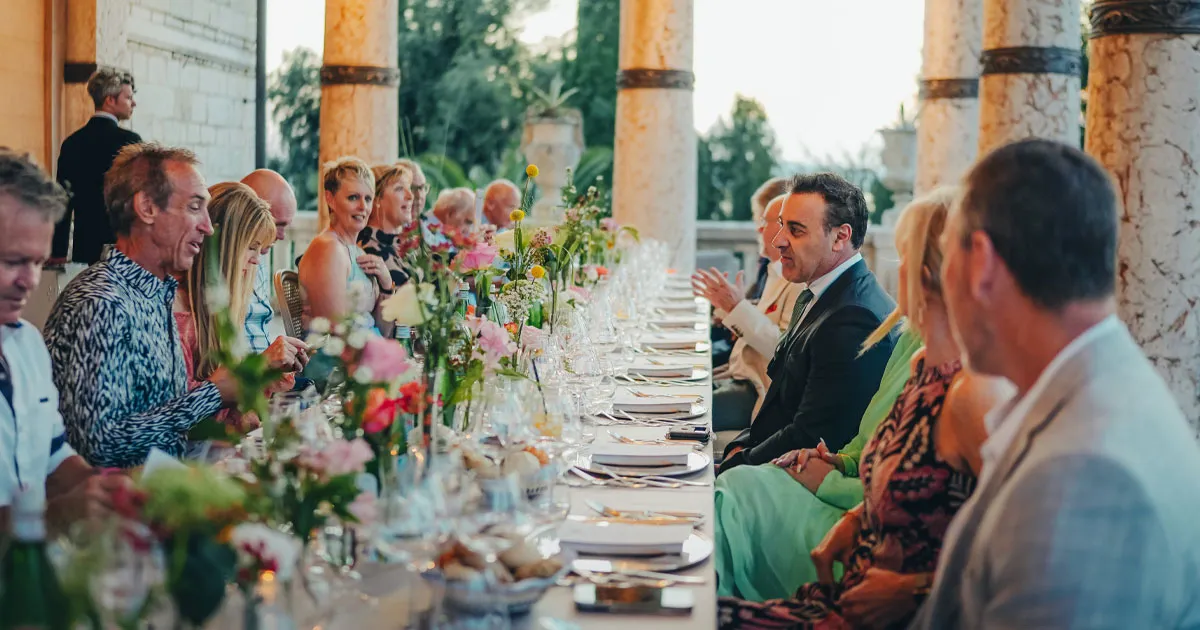 Ultimate Driving Tours guests enjoying lunch at a long and elegant table in Italy