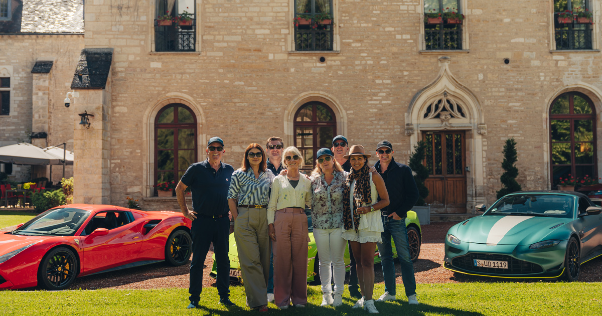A group of Ultimate Driving Tours guests pose happily in front of a chateau