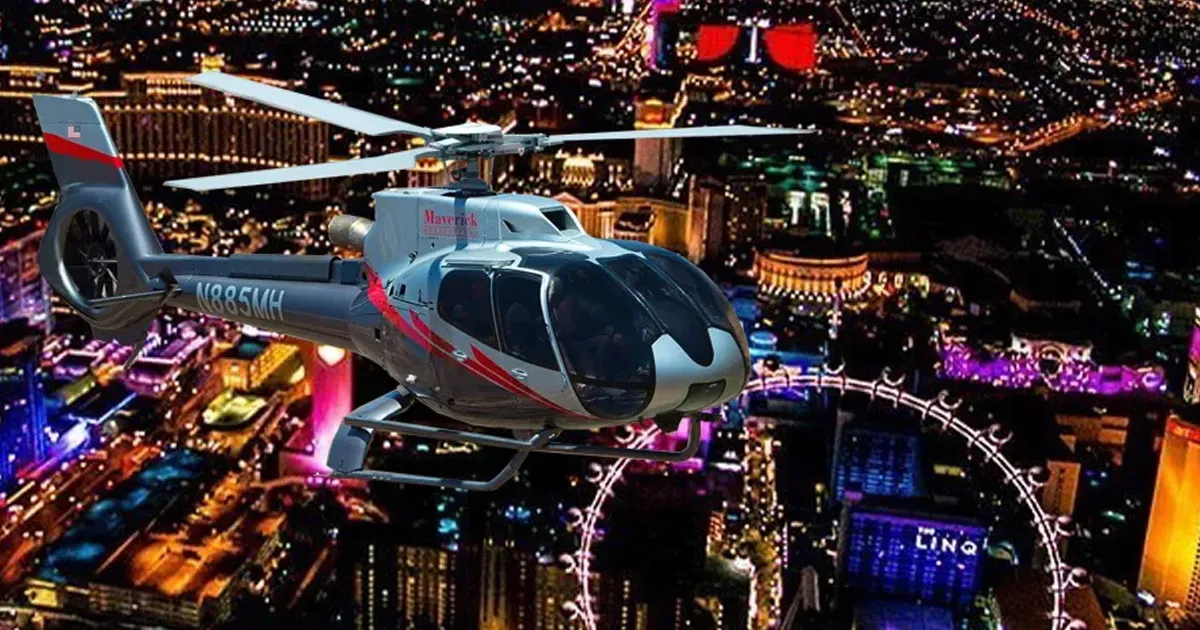 A helicopter flies above a ferris wheel in the night sky of Las Vegas.