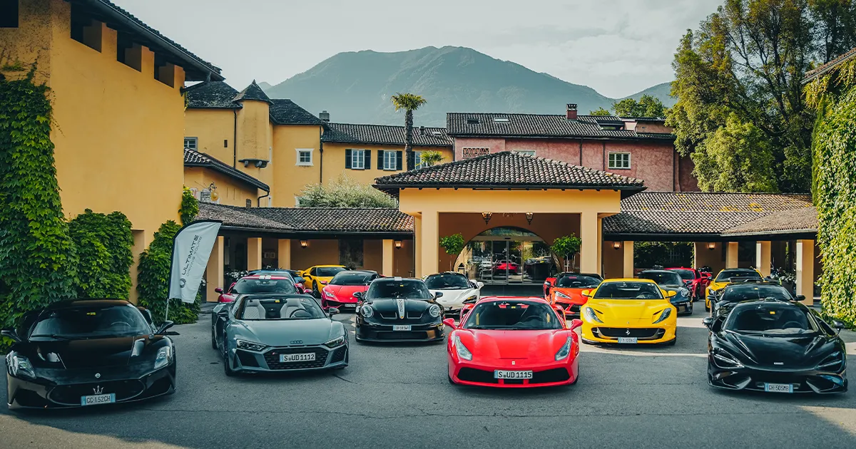 The Ultimate Driving Tours fleet of supercars sits outside a brightly coloured European luxury villa.