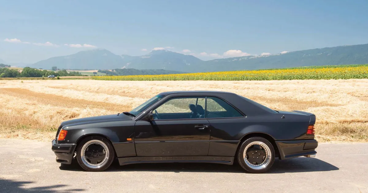 A black AMG Hammer sitting beside a paddock with mountains in the distance