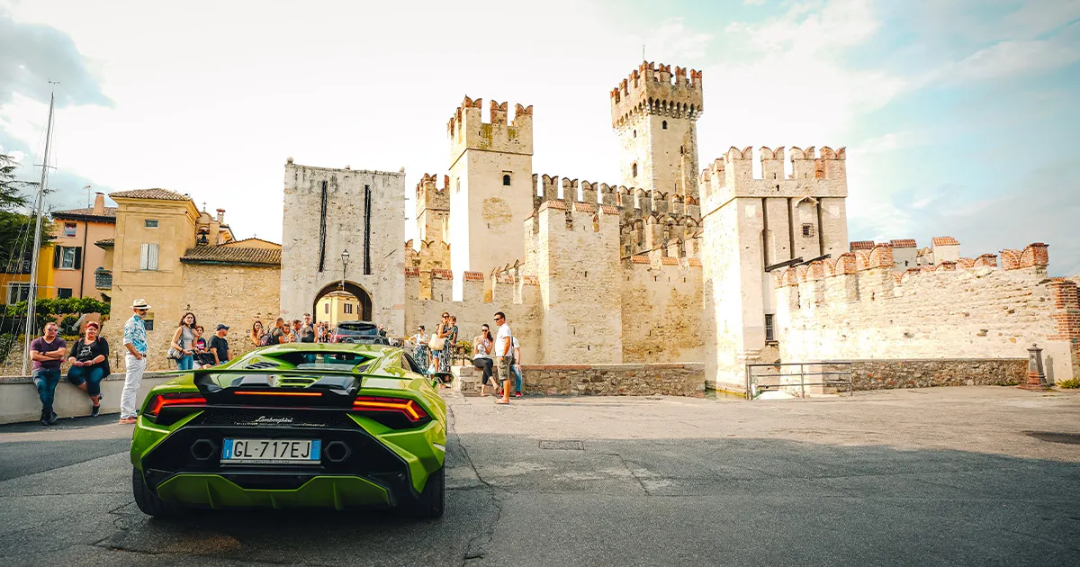 A green Huracán seen from behind as it sits outside an Italian castle.