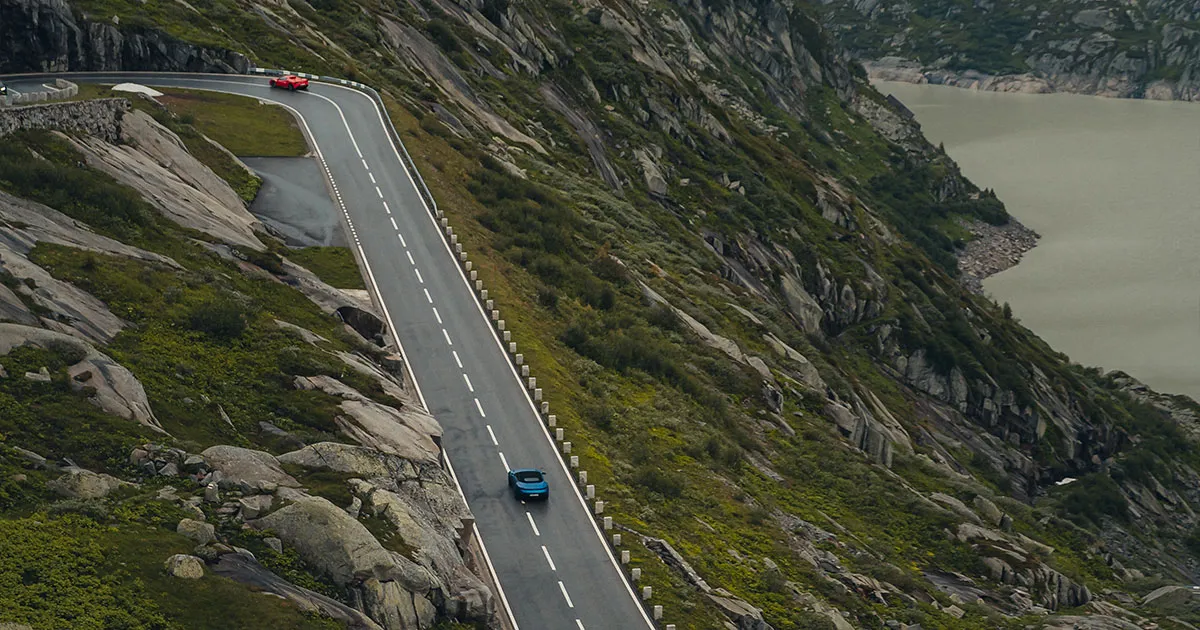 A lone blue supercar on an epic alpine road