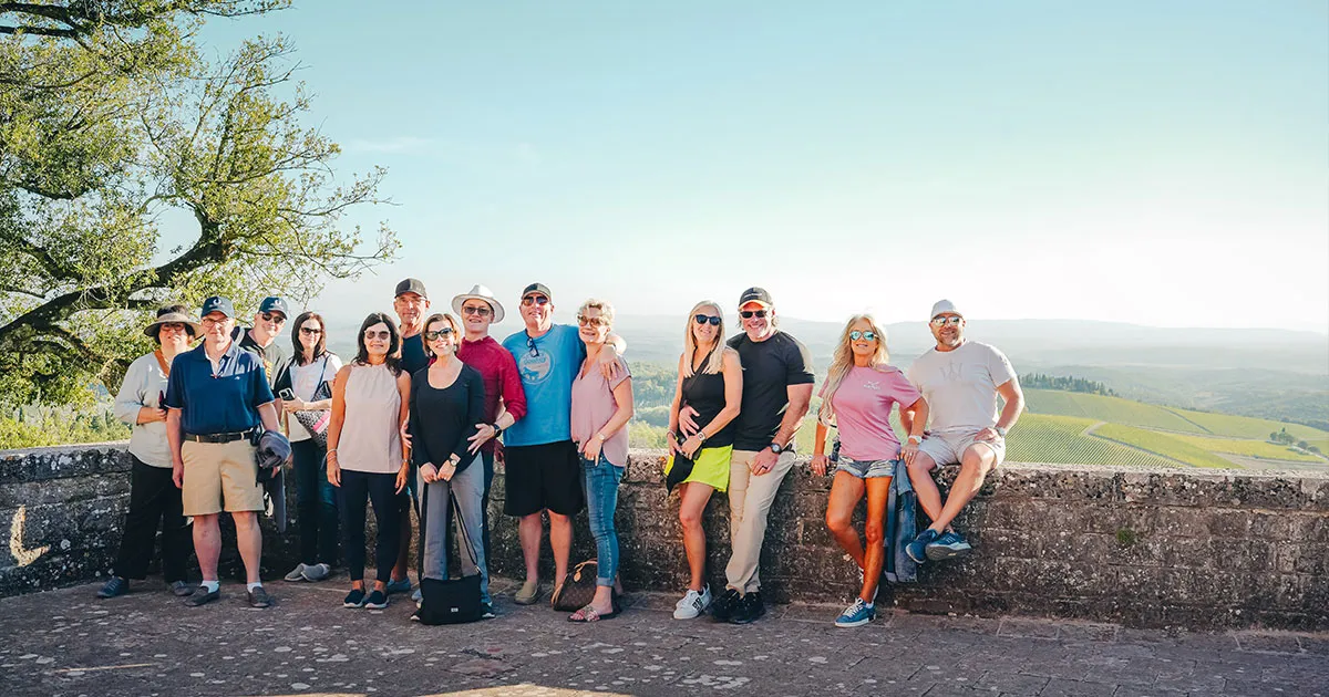 A happy group of Ultimate Driving Tours guests with scenic backdrop.