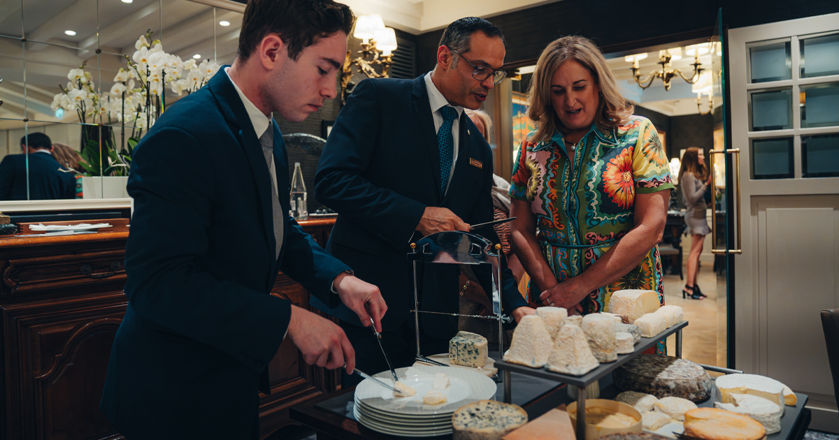 An Ultimate Driving Tours guest inspects the cheese cart at an upscale European restaurant