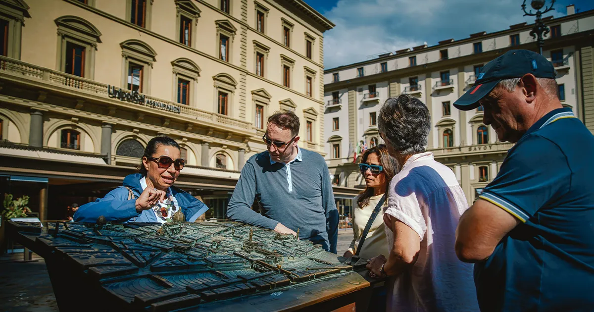 A female tour guide explains an ornate map to a small group of Ultimate Driving Tours guests.
