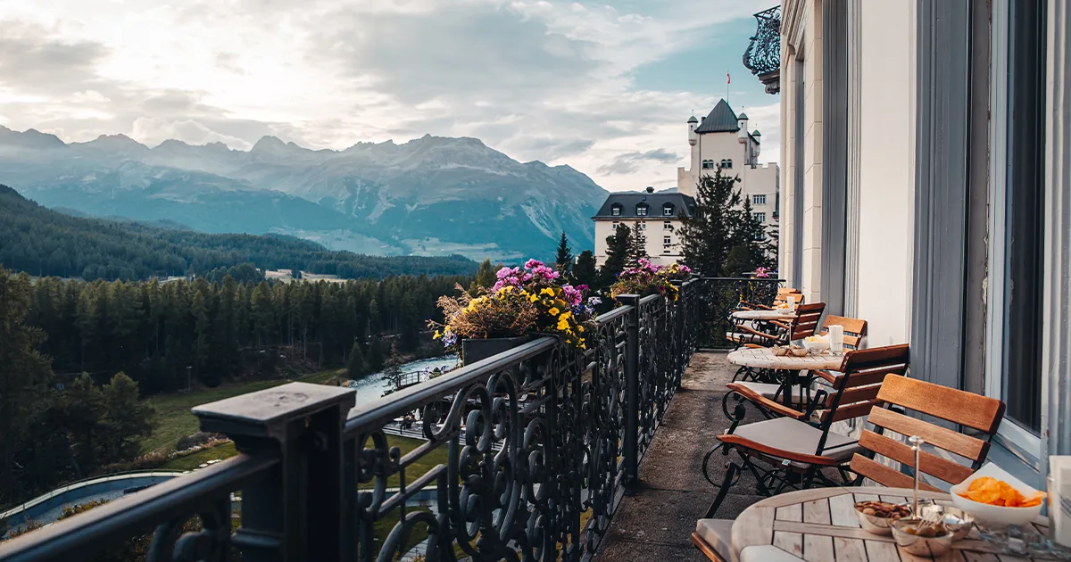 Expansive views from a luxury hotel balcony across a forested mountain valley.