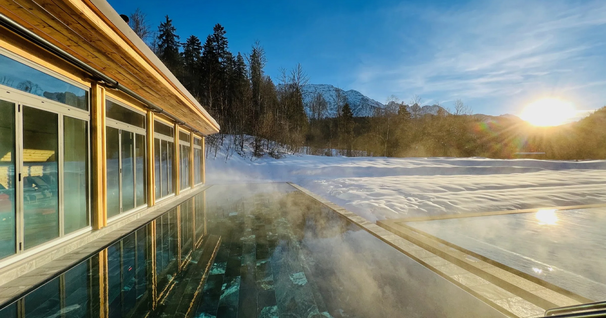 Steam rises from an outdoor spa pool in a snow-covered alpine resort
