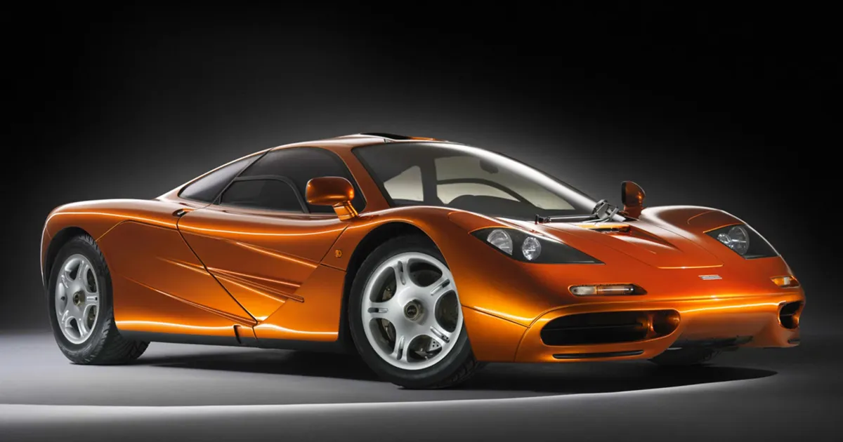 A metallic orange McLaren F1 in a studio with subtle lighting