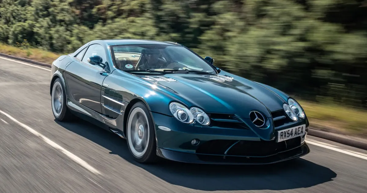 A teal McLaren-Mercedes AMG SLR supercar driving at pace on a country road.