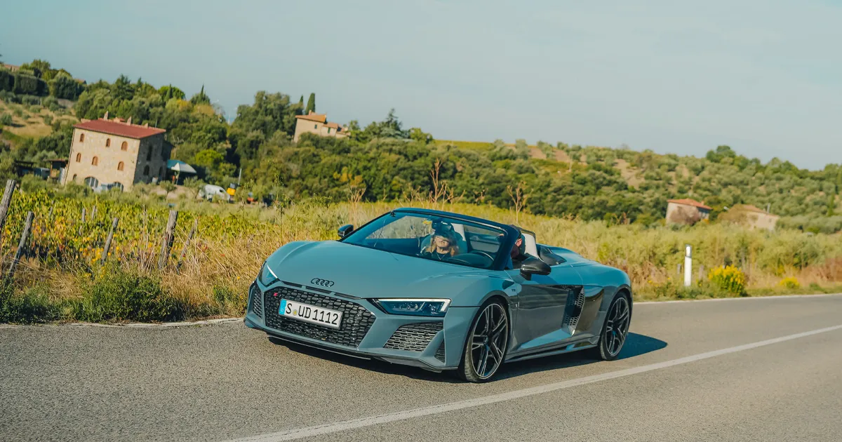 A dark teal Audi R8 V10 Spyder cruising past historic town