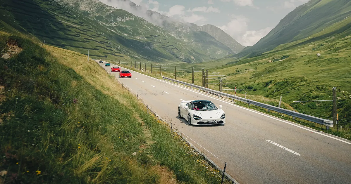 A convoy of Ultimate Driving Tours supercars led by a white McLaren 720S