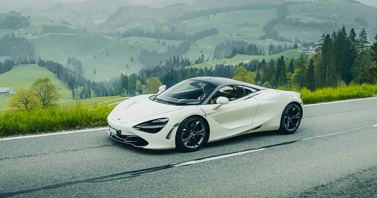 A white McLaren 720S on a high country road.