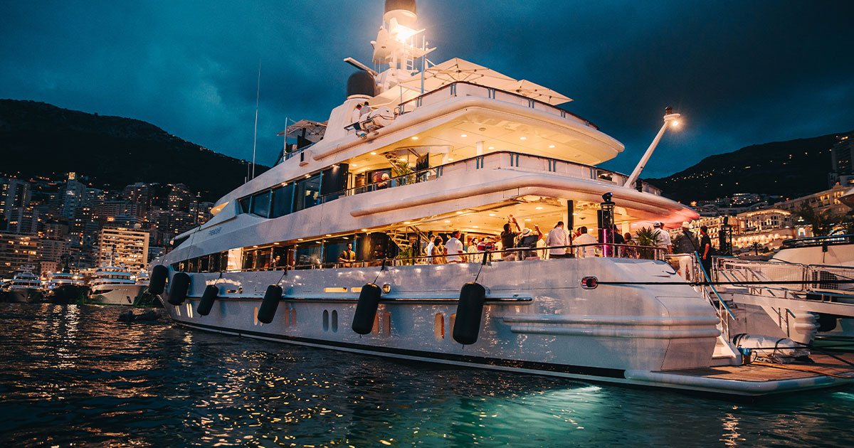 Ultimate Driving Tours private superyacht lit up at night in Monte Carlo