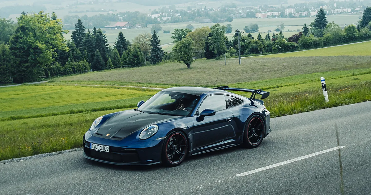 A blue Porsche 911 GT3 driving on a country road during an Ultimate Driving Tours luxury holiday.