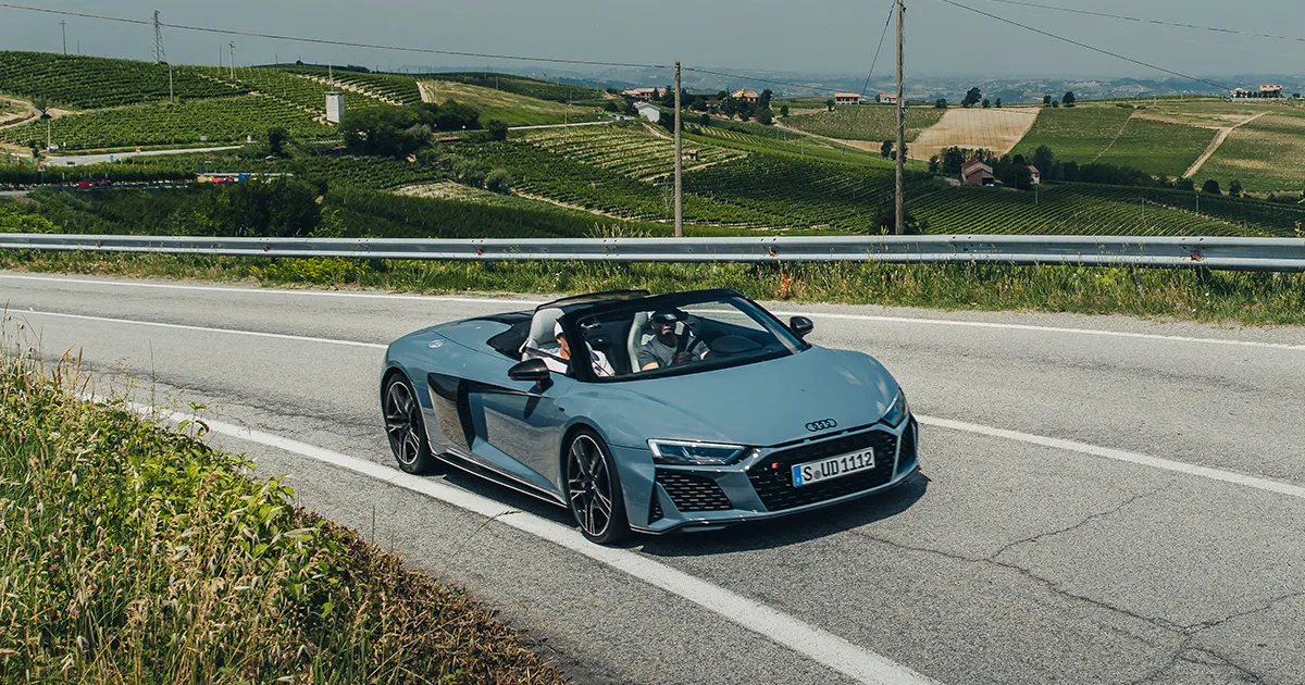 A grey Audi R8 convertible being driven through rolling hills by Ultimate Driving Tours guests.