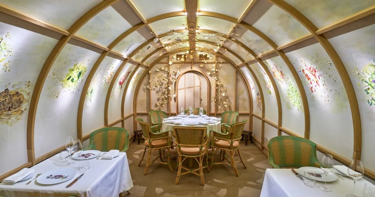 A small, ornate dining room with an unusual tunnel shape and artistic decor.