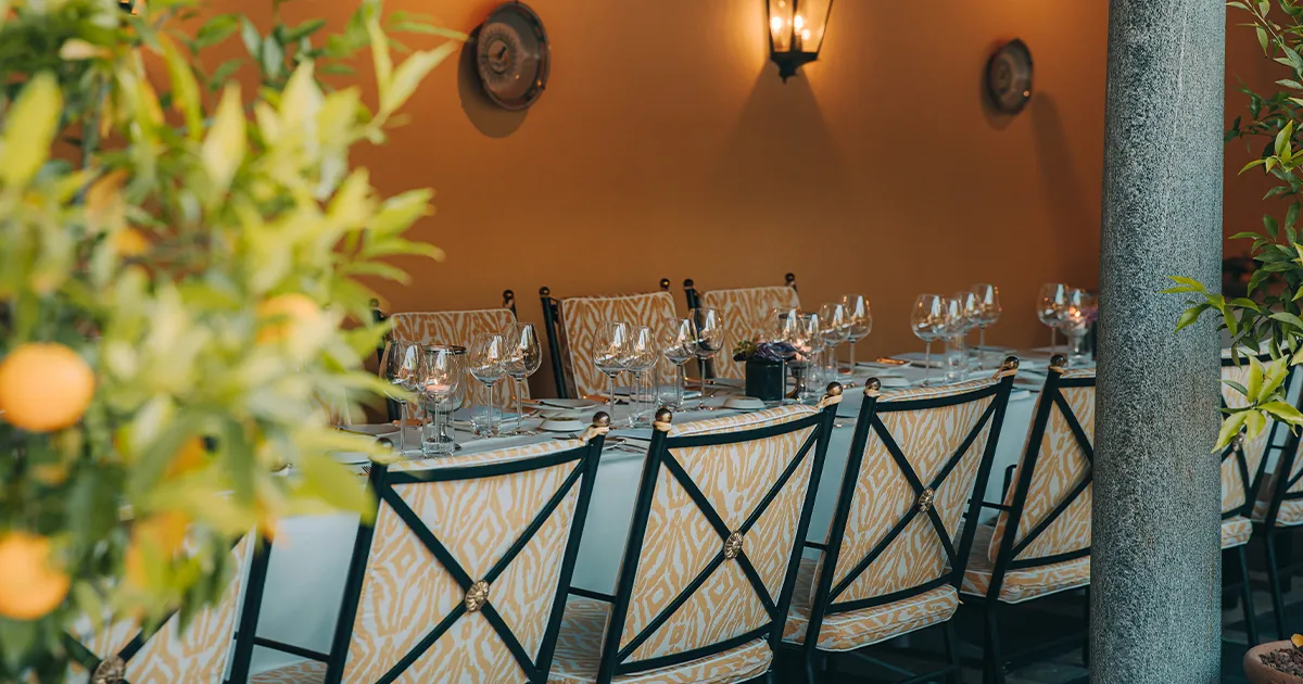 A long white-cloth dinner table in an al fresco courtyard setting.