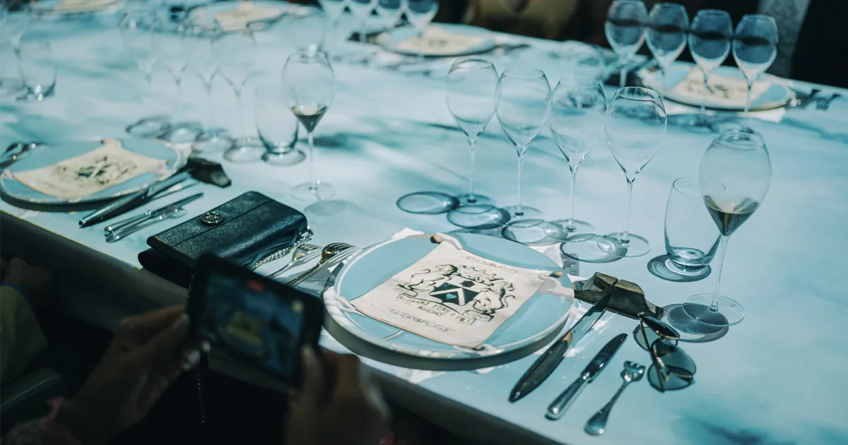 A formal dinner table setting adorned with many wine glasses and cutlery sets.