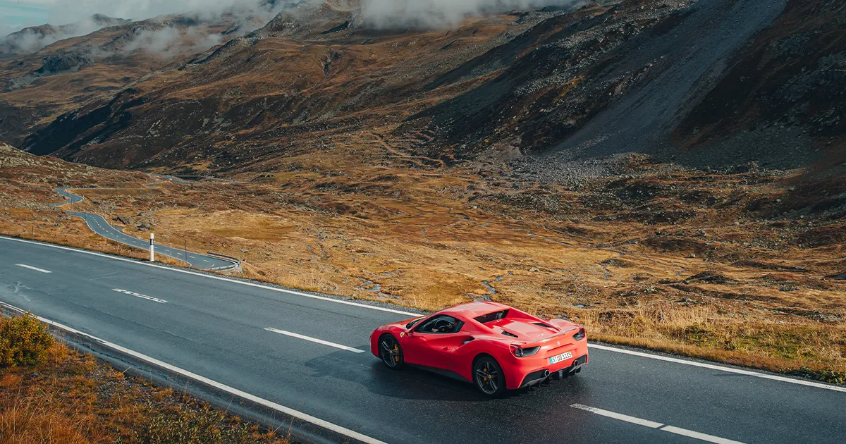 A red Ferrari 488 on an empty country road with barren landscape surrounds.