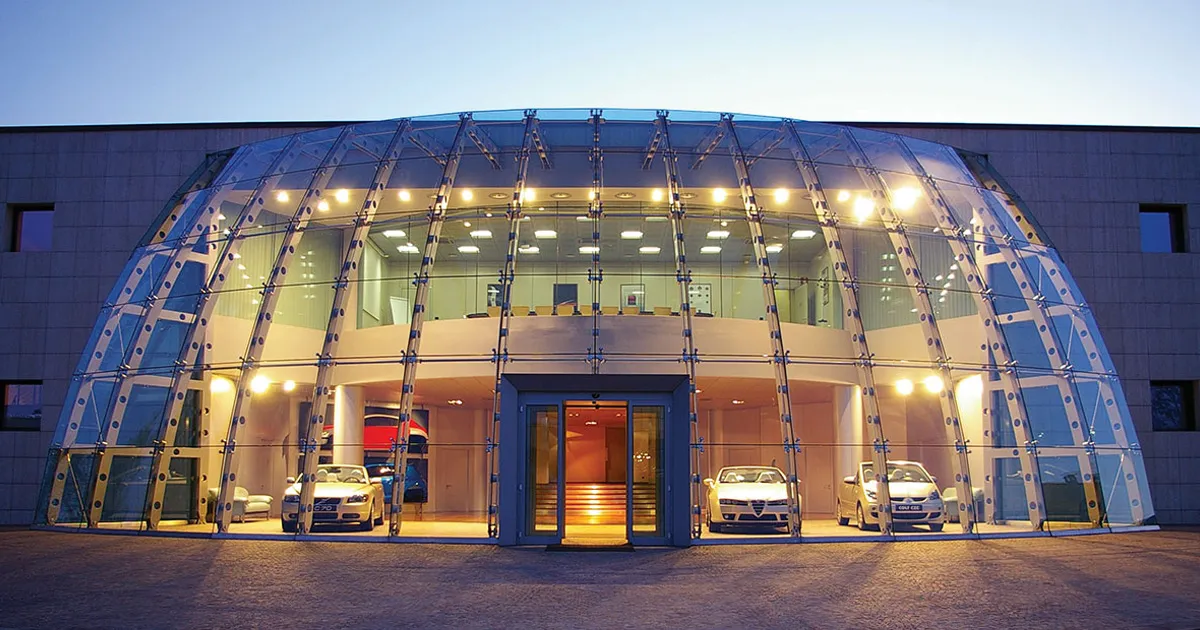 A large sculpted glass frontage displays several cars at Pininfarina HQ