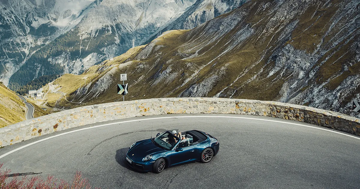 A convertible Porsche 911 rounds a bend in the mountains on an Ultimate Driving Tours supercar tour.