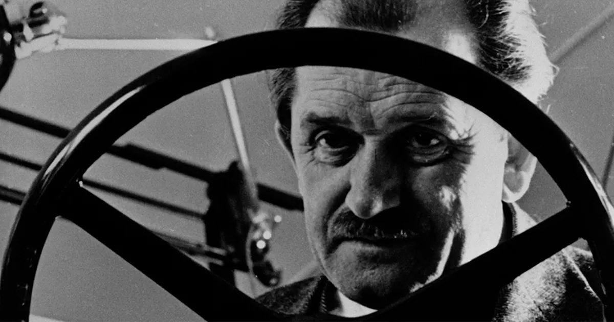 Professor Ferdinand Porsche as seen through the steering wheel of one of his creations.