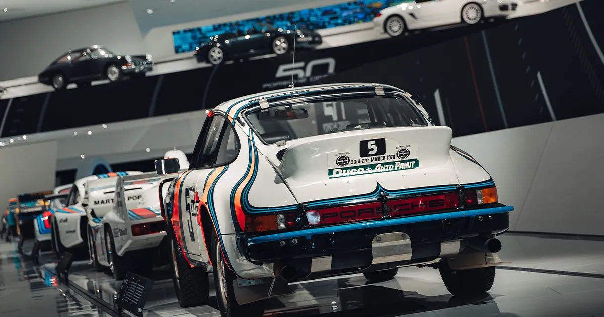 A white Porsche 911 racing car with Martini livery on display at the Porsche Museum, Stuttgart.