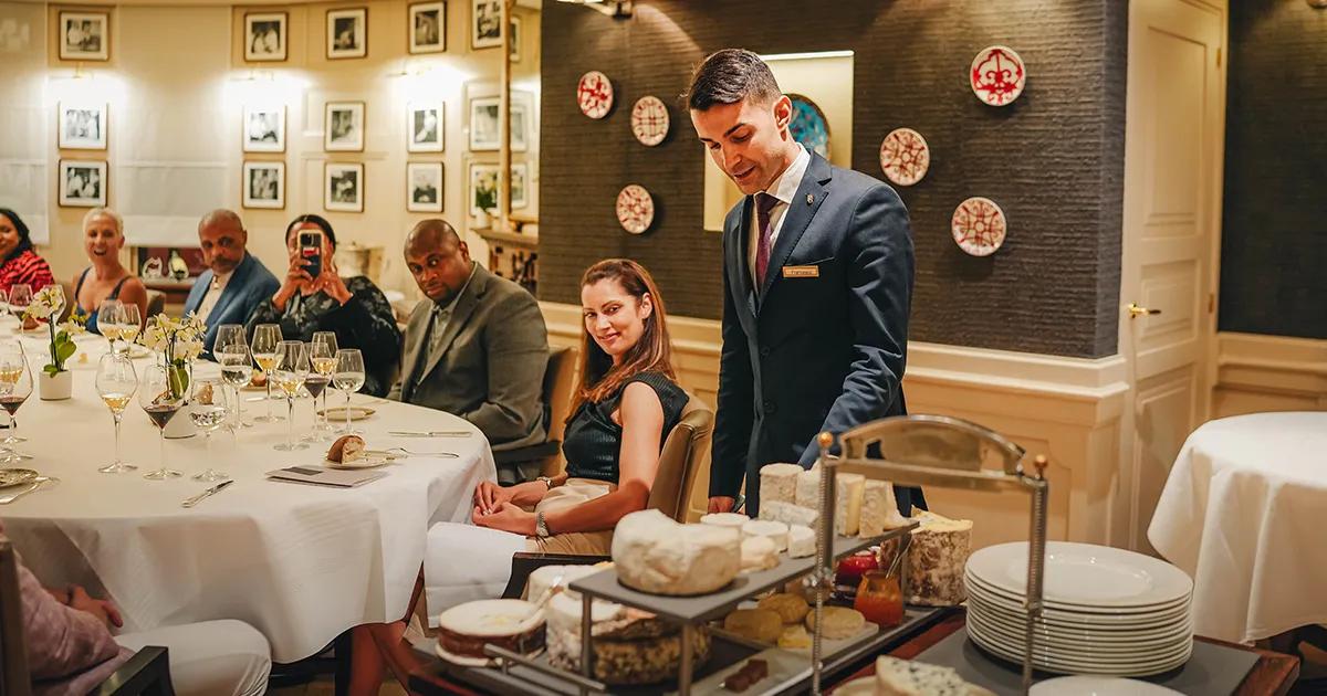 A group of guests watch on as a waiter explains the contents of the cheese cart at Restaurant Paul Bocuse.