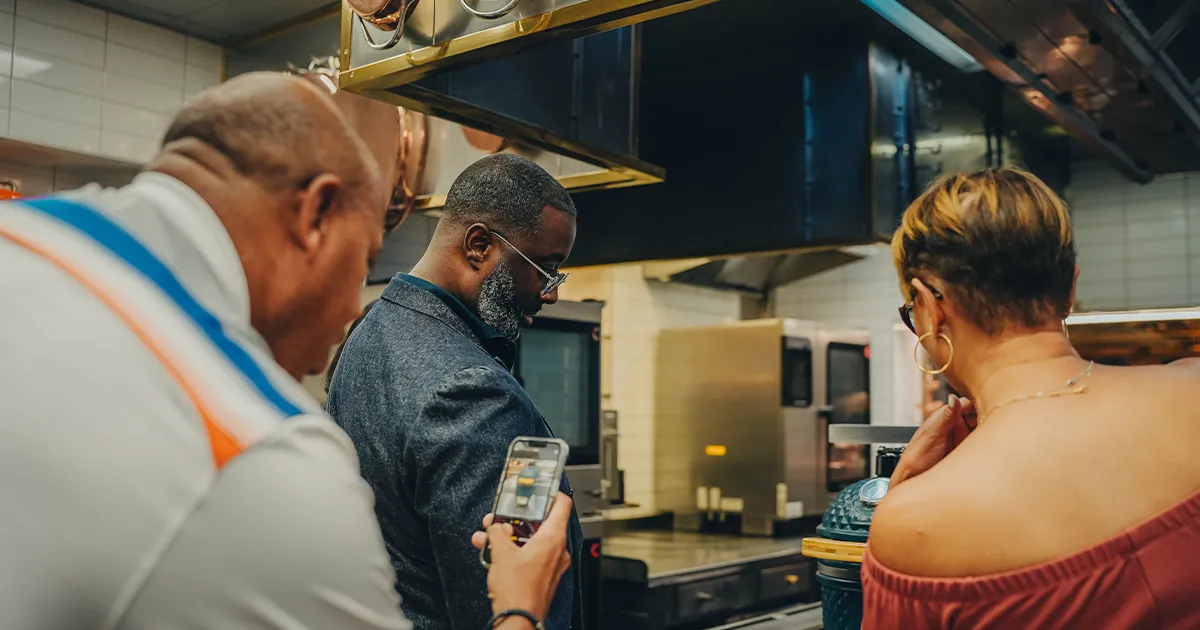 A small group of guests learning in the kitchen at Restaurant Paul Bocuse.