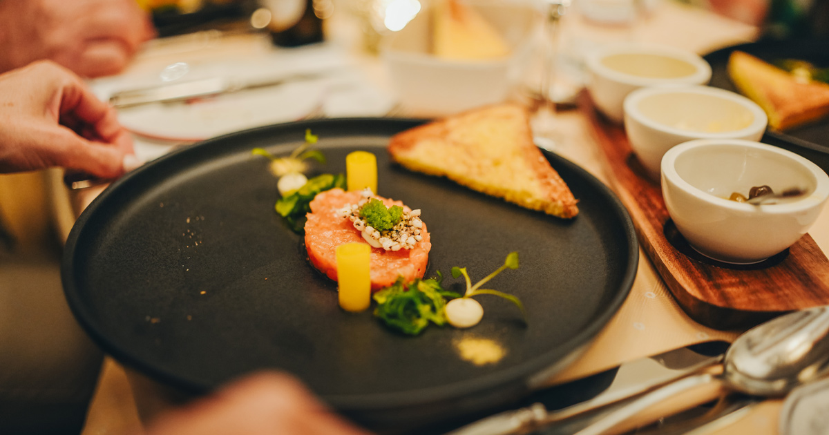 A black plate with an elegantly styled fish entree.