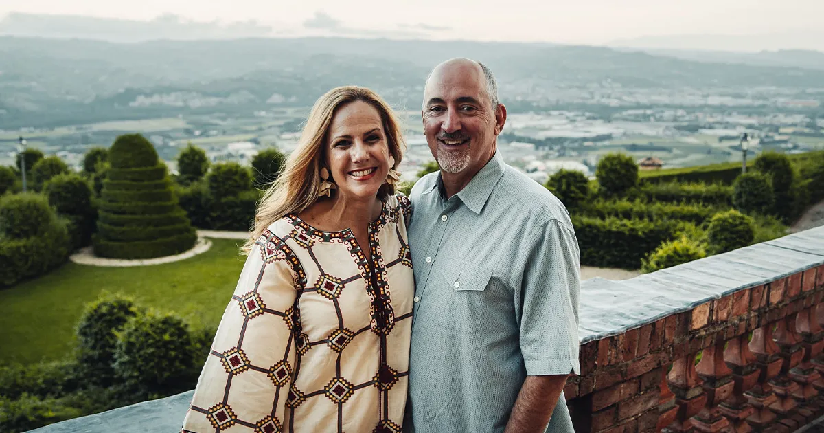 A happy couple pose in front of a sweeping valley backdrop.