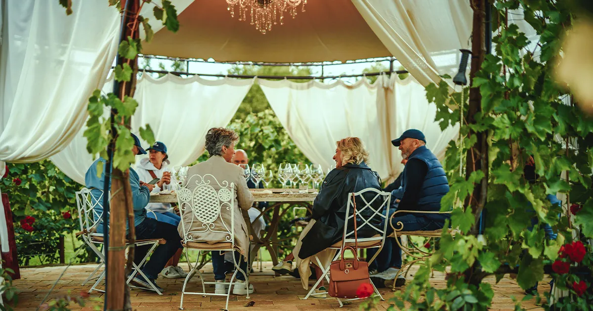 Guests enjoy an intimate meal under a pergola on a luxury driving tour.
